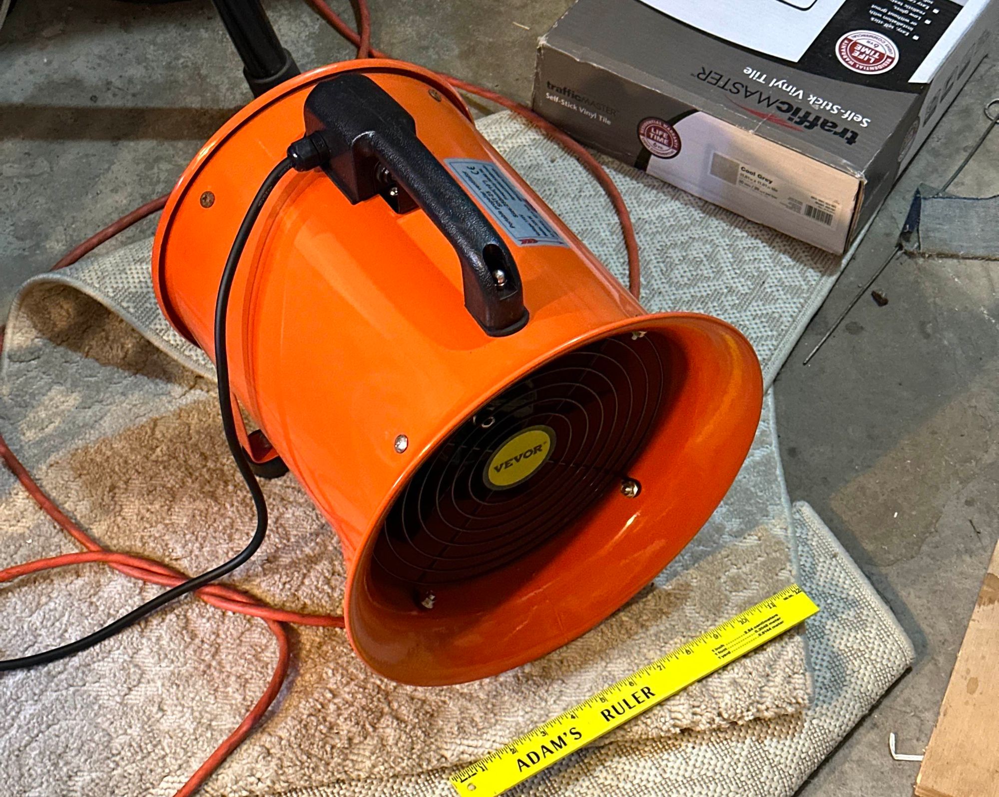 A large orange blower, with a ruler for scale showing the intake of the blower to be about a foot in diameter.