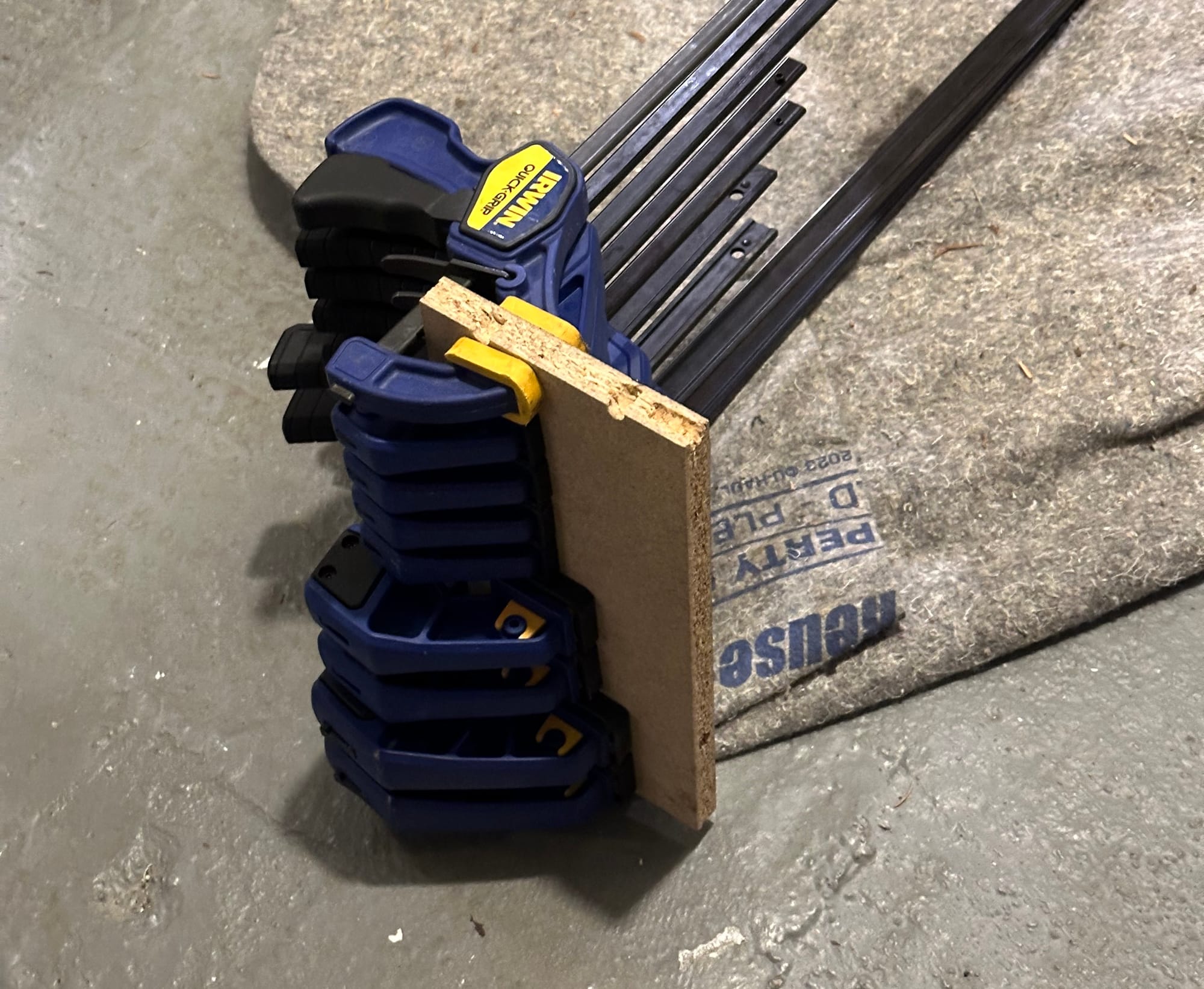 Irwin Quick-Grip clamps of various sizes, clamped on a piece of scrap wood in a row