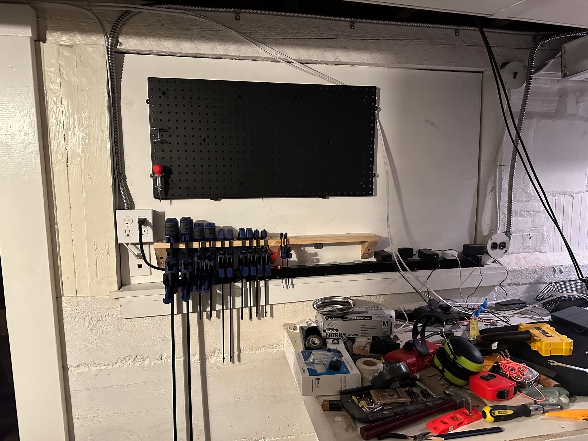 Clamp solution in place populated by clamps, with additional workshop starting to take shape around, including power strip and pegboard