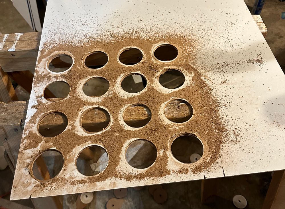 An in-progress photo, showing a 4x4 grid of large holes drilled into a piece of tile board.